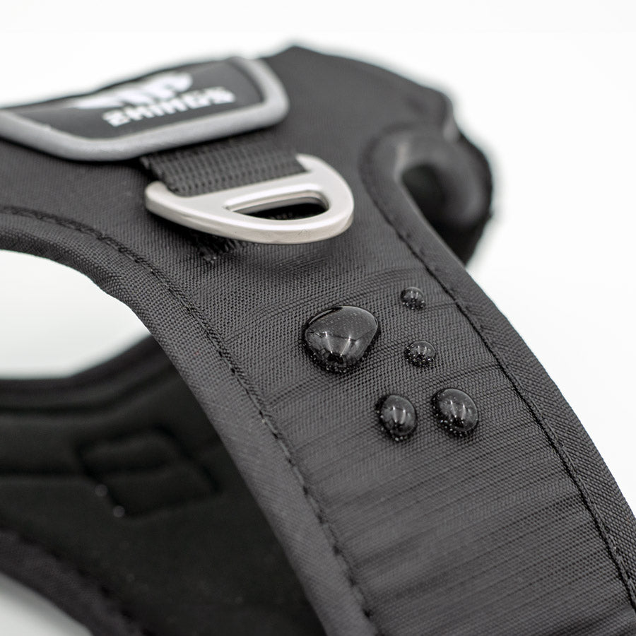 Close-up of the waterproof feature on a black dog harness, with padded, adjustable design and top handle for comfort and control.